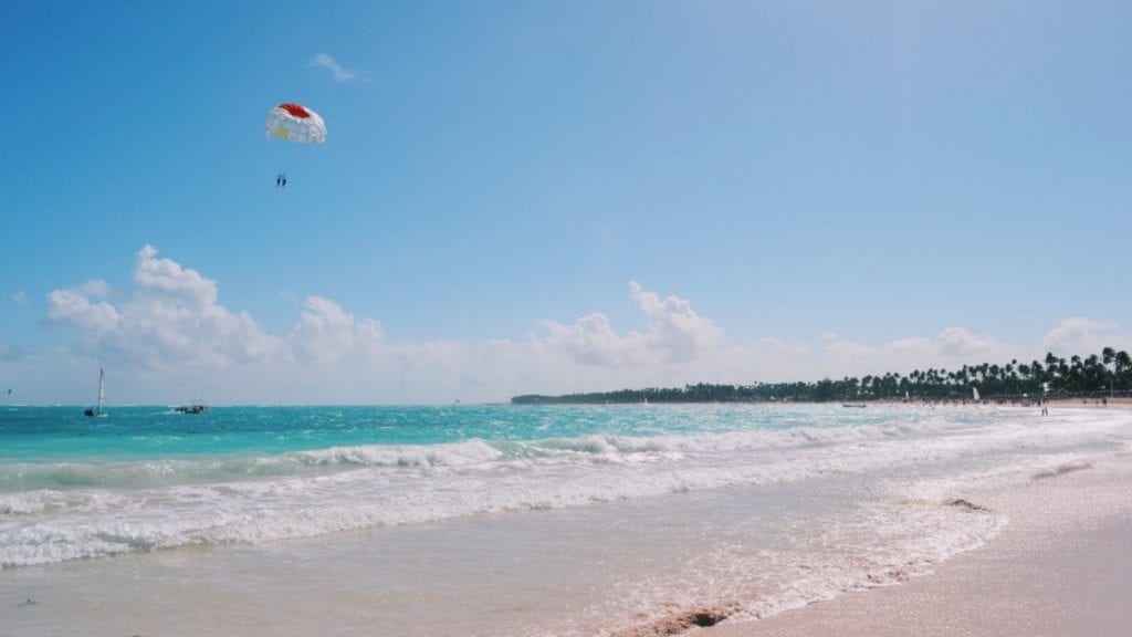 Punta Cana beach with waves and parasailers in background