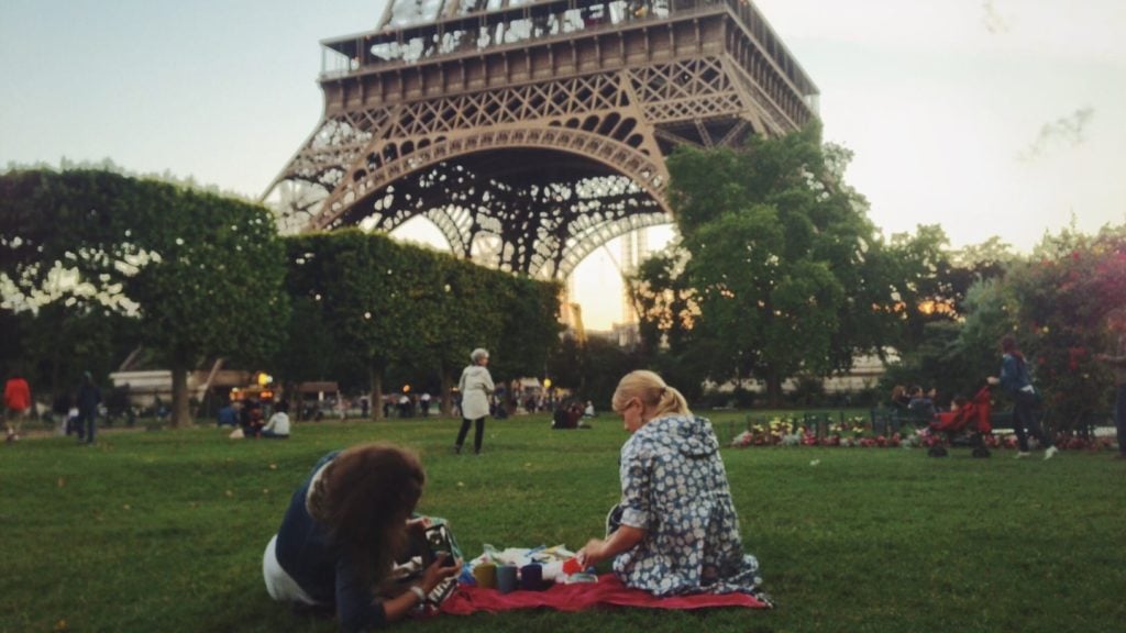 two people picnicking beside the Eiffel Tower at dusk. The Eiffel Tower is a top Europe tourist attraction