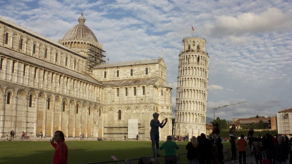 Leaning Tower of Pisa with a crowd posing in front of it. The tower is one of the top Europe tourist attractions