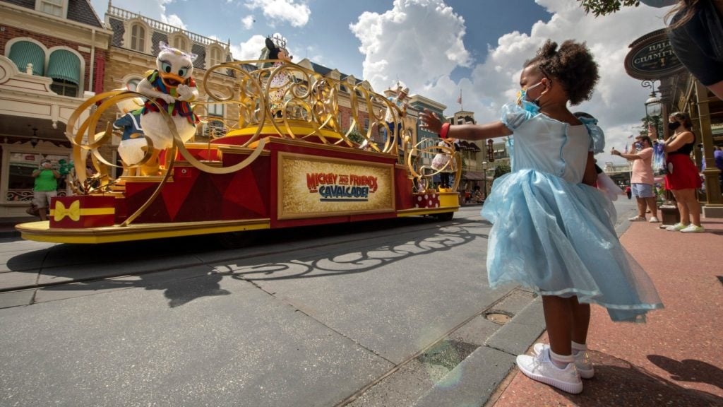 Toddler wearing a dress watching the parade at Walt Disney World's Magic Kingdom, an amusement park for kids that caters to toddlers