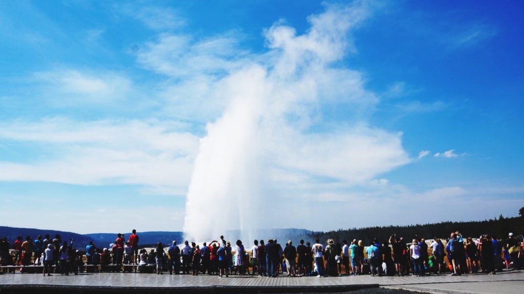 Crowd watching Old Faithful Geyser in Yellowstone National Park. The geyser is one of the top U.S. tourist destinations