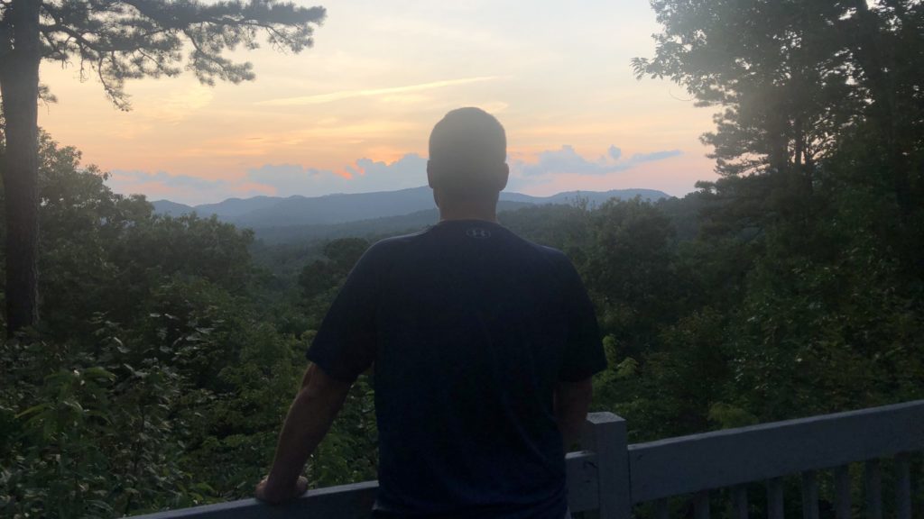 Man looking out at the sunset from Angie's Mountain Overlook vacation rental in Asheville, North Carolina