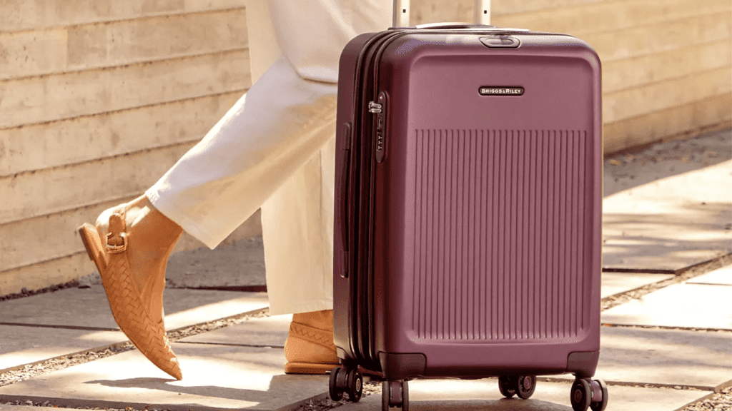 close-up of purple Briggs & Riley hardsided suitcase and person's legs