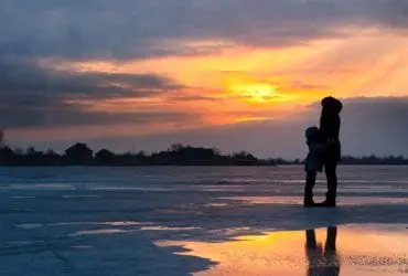 woman and child on cold beach at sunset