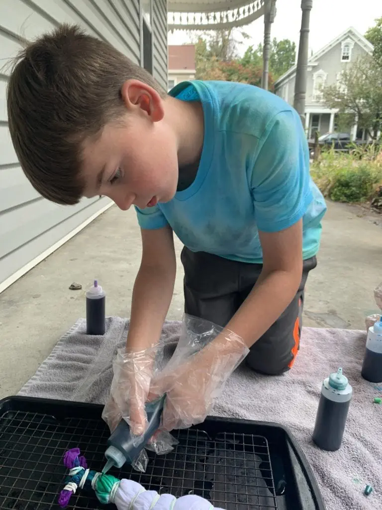 Child applying colors to a Mickey Mouse tie dyed t shirt