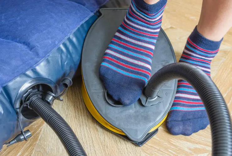 A woman with air foot pump pumps an inflatable mattress. (Photo: Yevhen Prozhyrko/Shutterstock)