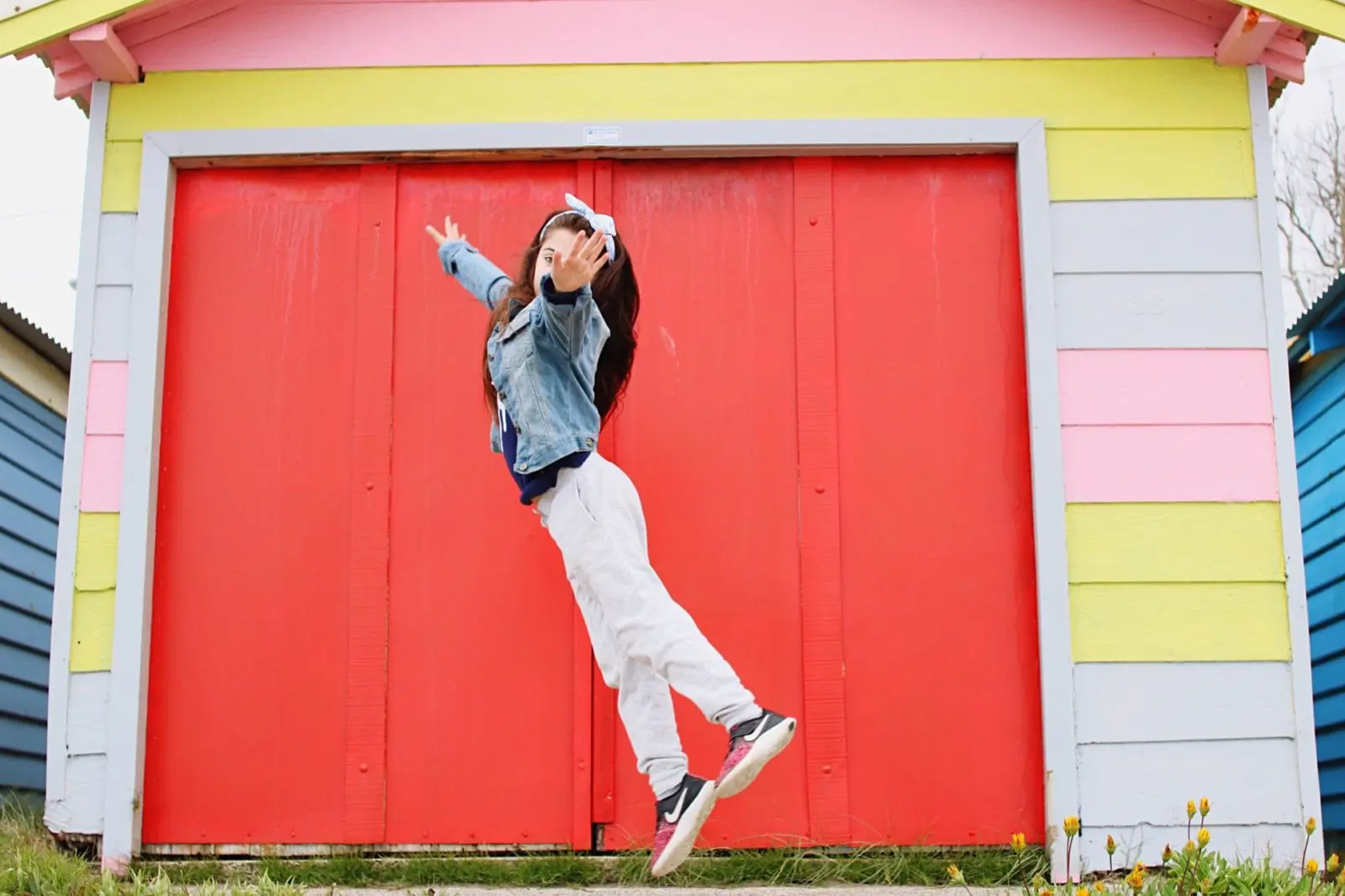 girl in sneakers jumping in front of colorful house