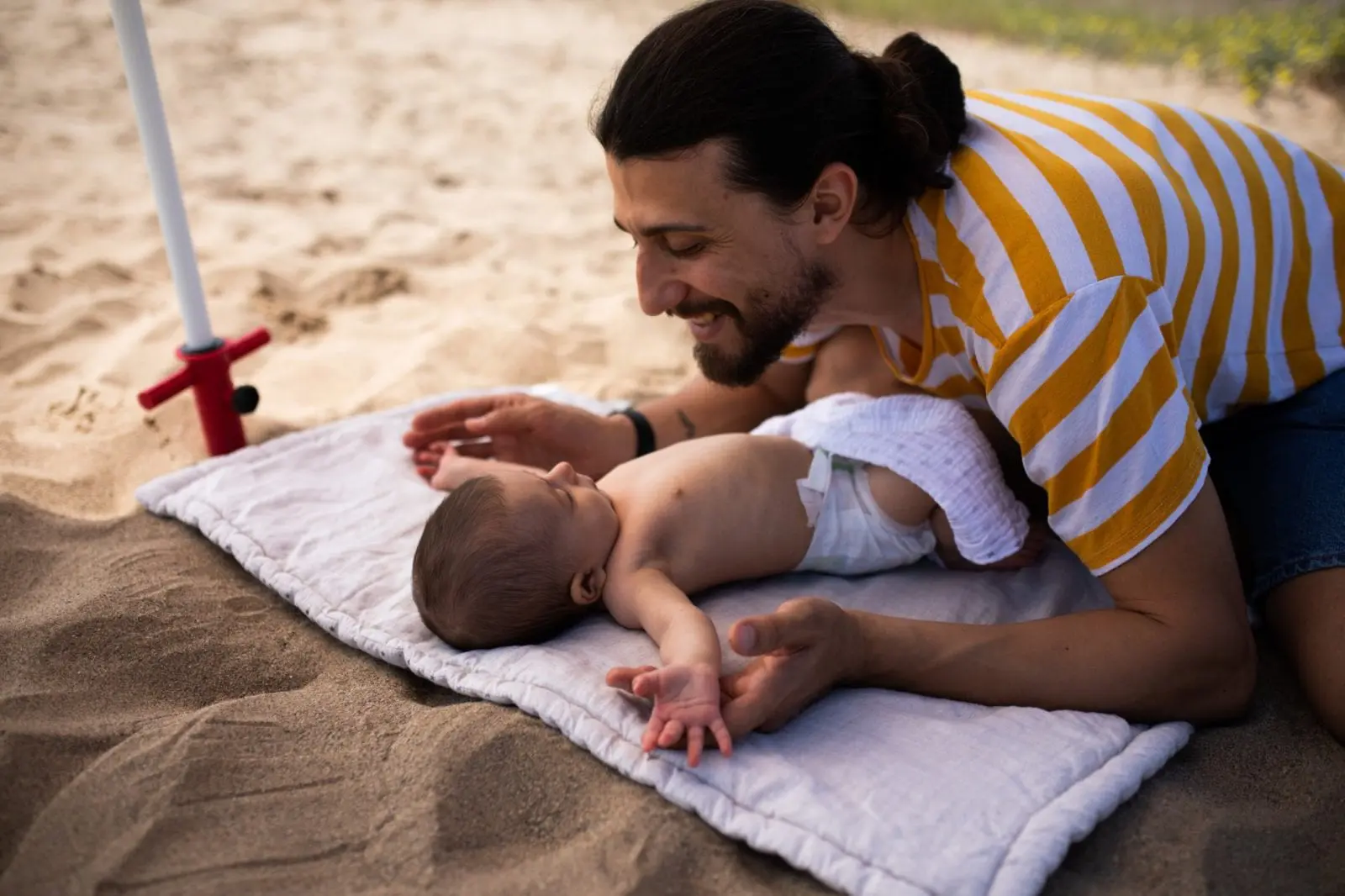 parent playing with baby at the beach: best baby sunscreens