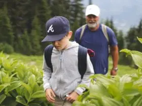 A boy and his grandfather on a skip-gen vacation hiking through an alpine meadow (Photo: @jordvdz via Twenty20)