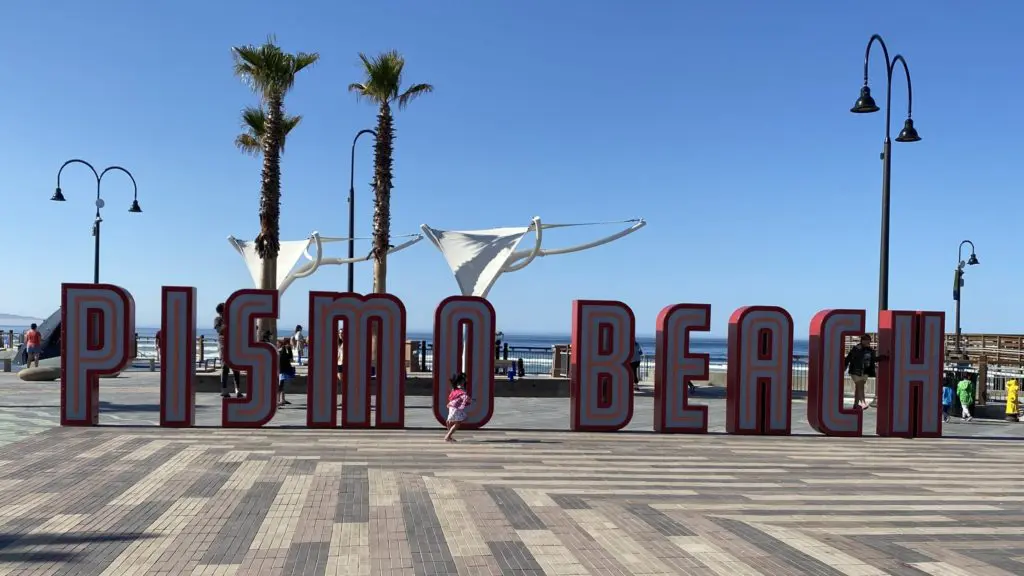 Pismo Beach sign at the Pismo Beach Pier with palm trees in background
