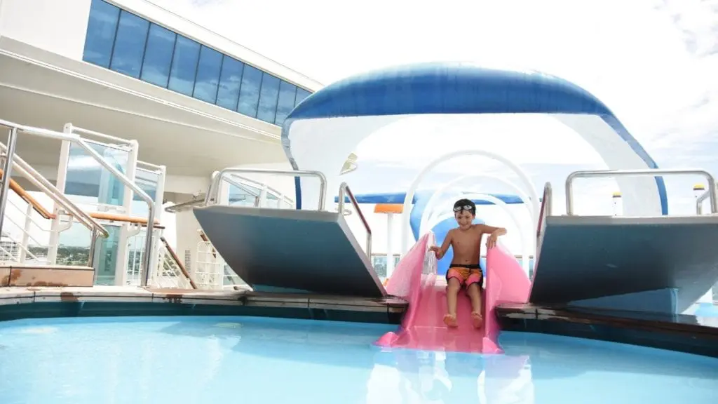 Child going down slide into pool on cruise ship