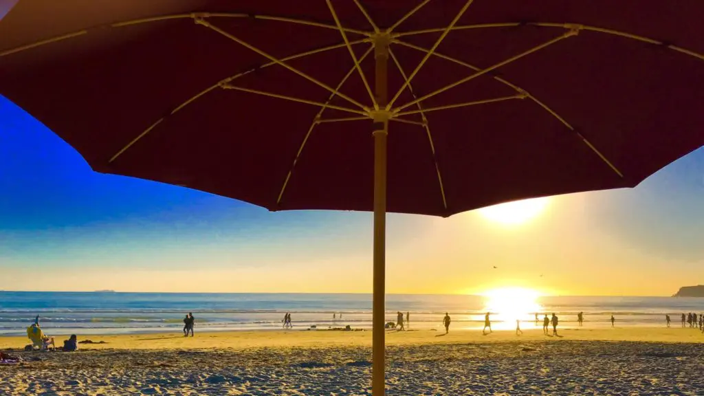 View of beach and water at sunset from under a beach umbrella in Coronado, California, a skip-gen vacation destination