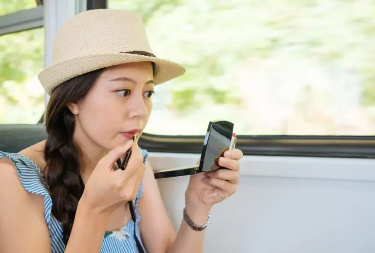 Woman repairing makeup with multi-use beauty products (Photo: Shutterstock)