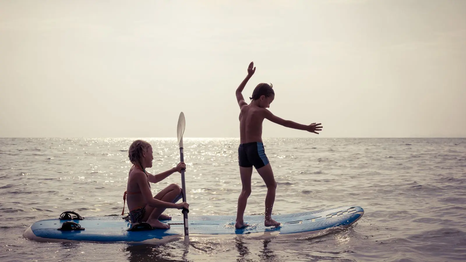 kids playing on a paddleboard in the water