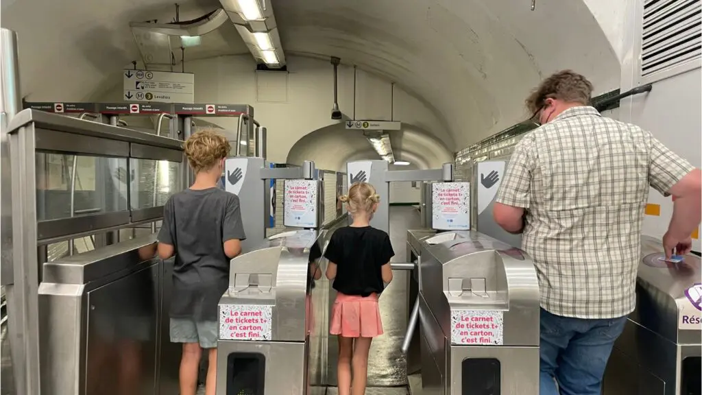 two kids and a dad going through the turnstile on the Paris metro