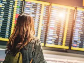 Woman in airport terminal looking at arrivals and departures board (Photo: Shutterstock)