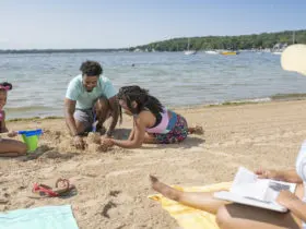 family on Midwest vacation building a sandcastle on the beach