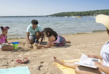 family on Midwest vacation building a sandcastle on the beach