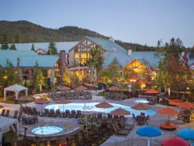 Exterior view of the Tenaya Lodge at Yosemite, with pools and trees in the foreground of the family friendly California resort