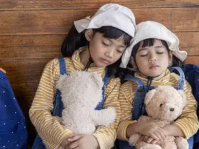 Two jet lagged children holding teddy bears and napping on a train (Photo: Envato:FamilyStock)