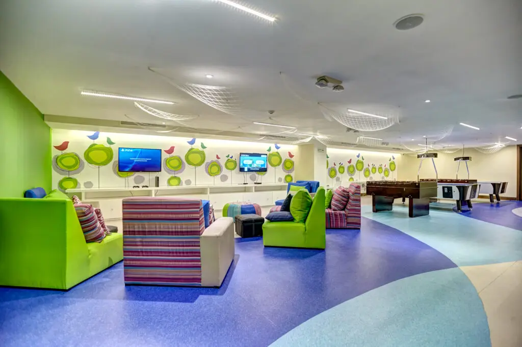 Colorful chairs and TVs for playing video games and table games in the kids club at Royalton Riviera Cancun
