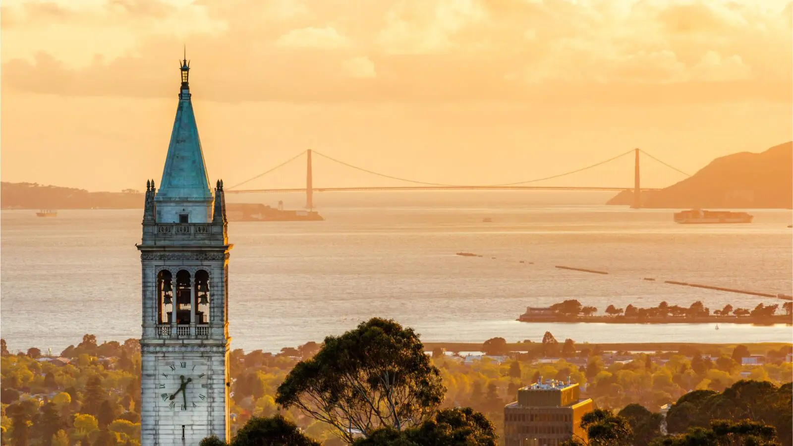Sather Tower at UC Berkeley campus, with Berkeley and the Golden Gate Bridge in the background.