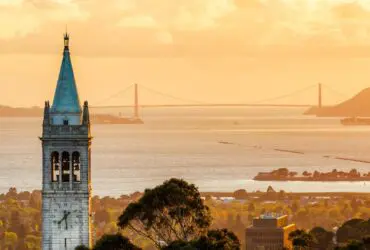 Sather Tower at UC Berkeley campus, with Berkeley and the Golden Gate Bridge in the background.