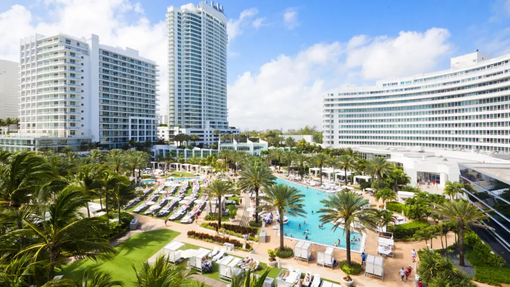 Une vue sur la piscine principale avec beaucoup de chaises qui l'entourent à Fontainbleau Miami Beach