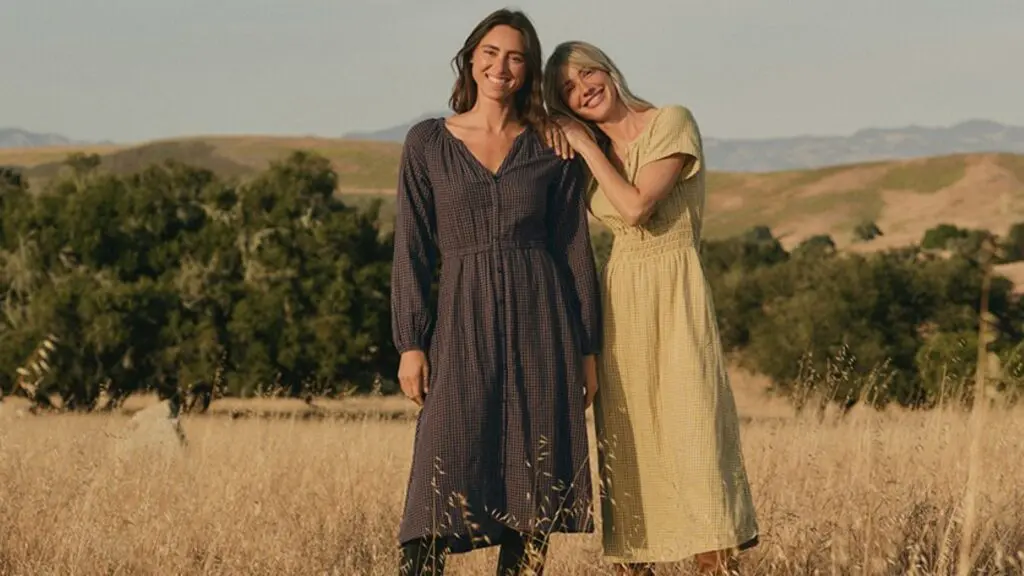 Two women standing in a field in dresses from Pact