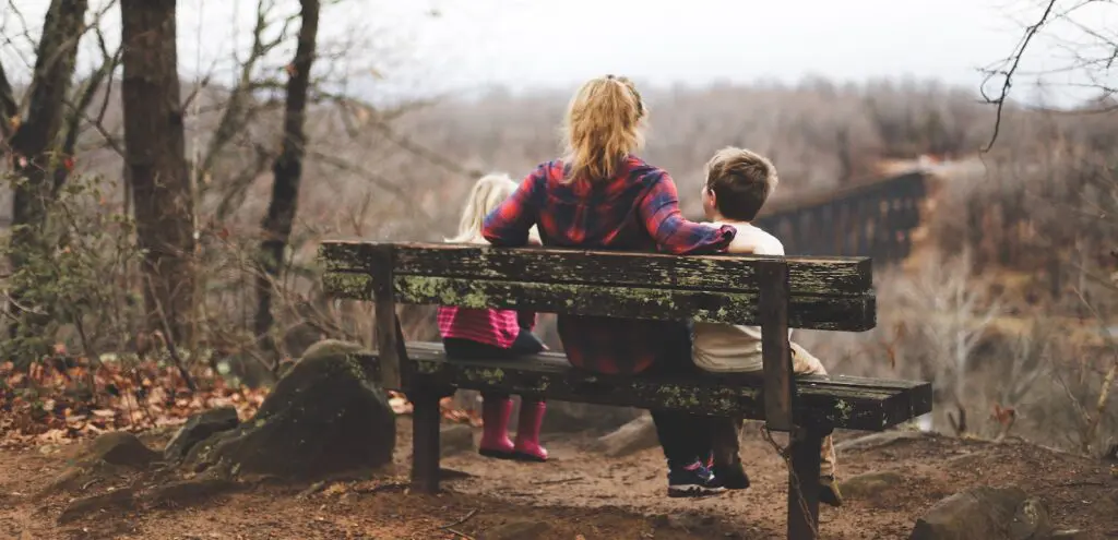 Mom and two toddlers sitting on park bench