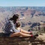 Parent and toddler perched on a wall looking out over the Grand Canyon (Photo: Envato/westend61)