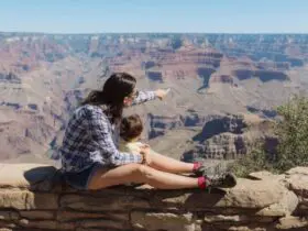 Parent and toddler perched on a wall looking out over the Grand Canyon (Photo: Envato/westend61)