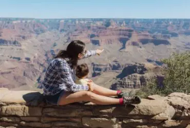 Parent and toddler perched on a wall looking out over the Grand Canyon (Photo: Envato/westend61)