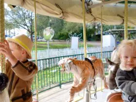 a baby and a toddler riding a carousel at the Oakland Zoo in California