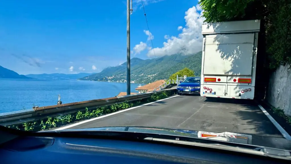 narrow road with cars passing a truck in a tight spot along the banks of Lake Maggiore