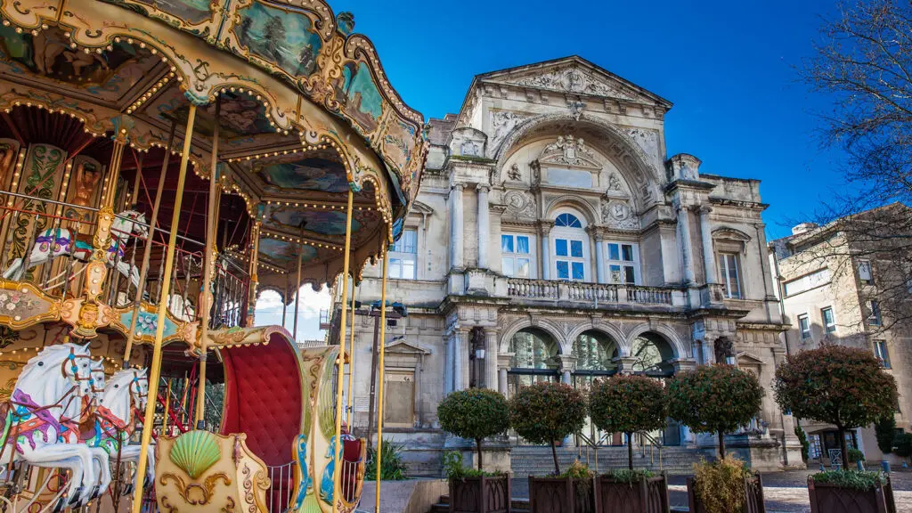 Carousel adorned with lights, in front of an old stone building
