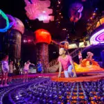 Kids play in dark, colorful space with planet structures hanging from the ceiling