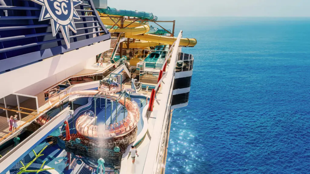 Waterslides tower over the top deck of a cruise ship sailing in the middle of the sea