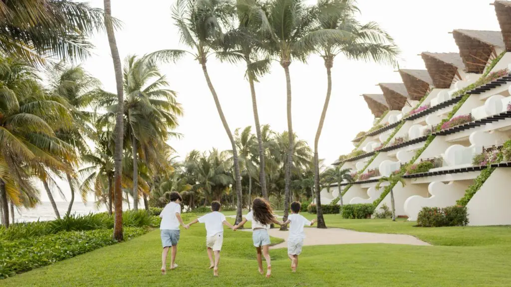 Four kids running on the grass at Grand Velas Riviera Maya
