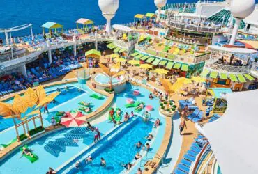 Swimming pool surrounded by many deck chairs on cruise ship