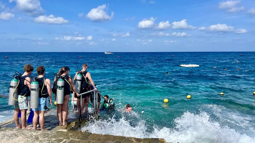 people lined up on the water's edge to scuba dive in the Caribbean