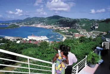 Couple standing on hill overlooking a bay with cruise ship and mountains in the background