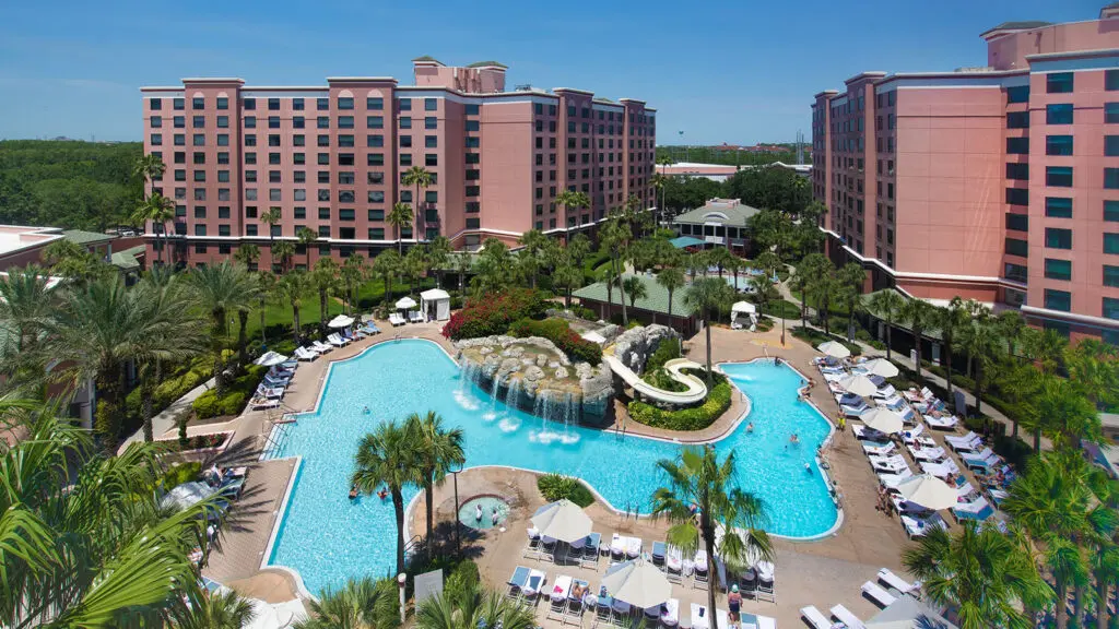 Two resort buildings with a swimming pool surrounded by palm trees