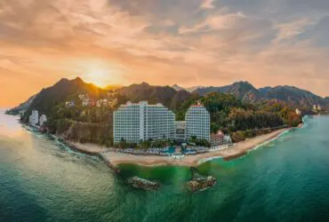 Hotel on mountainous coastline at sunset