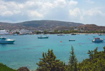 Fishing boats anchored in bay with mountains and small village in background