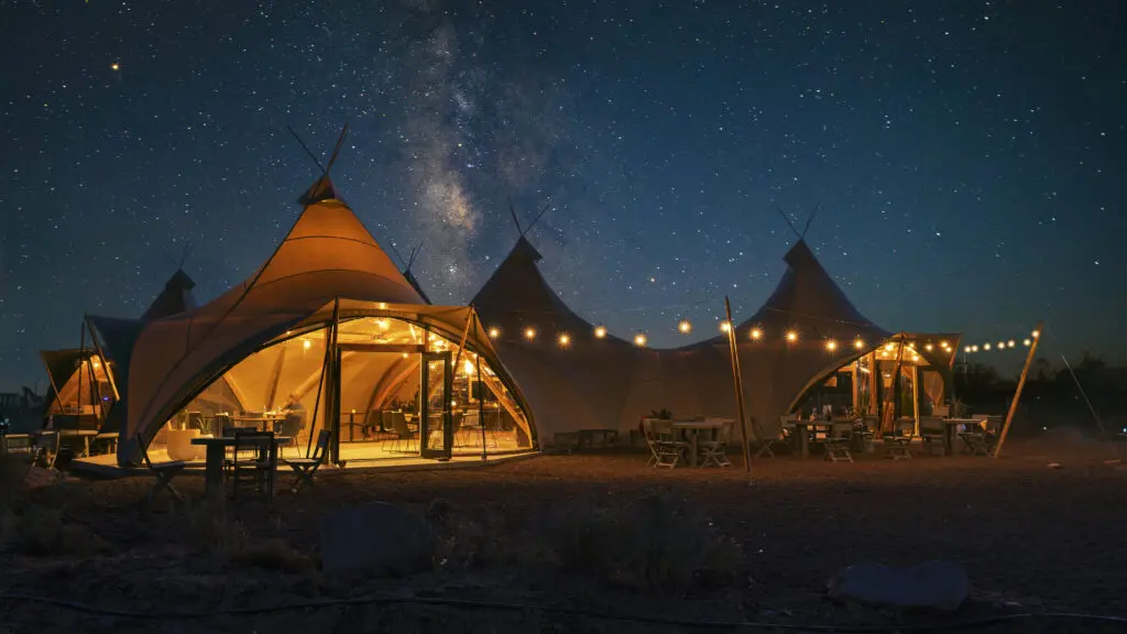 The common area tents at Under Canvas Grand Canyon at night with strong lights and the stars overhead