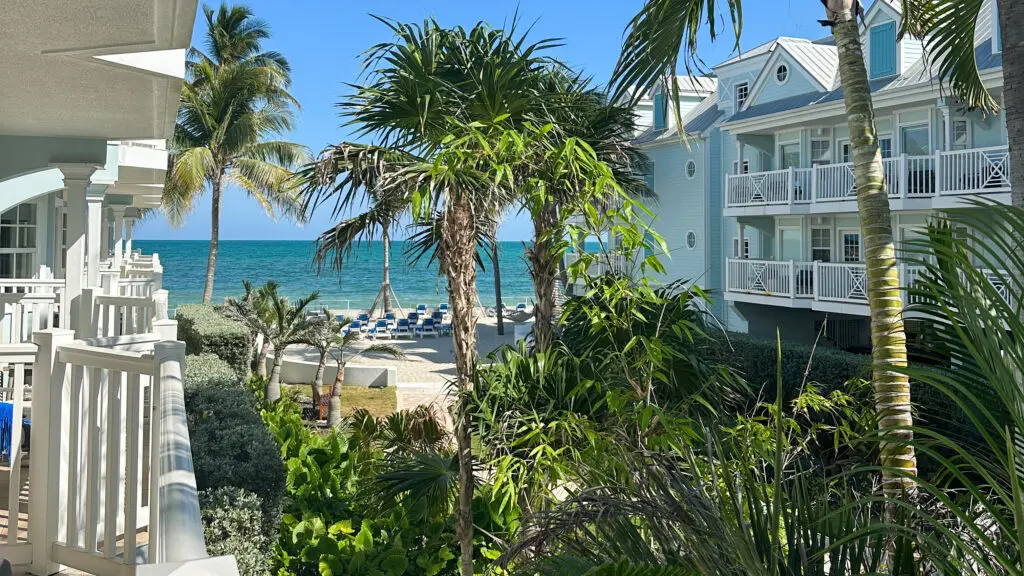 The view from a balcony at Southernmost Beach Resort of a grassy courtyard with palm trees and the Atlantic Ocean in the distance