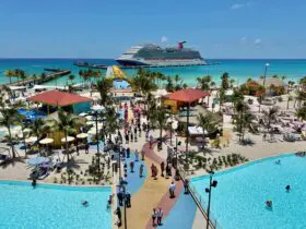 Cruise ship docked at island with many buildings and a pool in the foreground