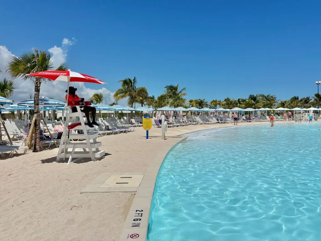 Juruselamat menghadap ke kolam renang dengan kursi dek dan payung di latar belakang