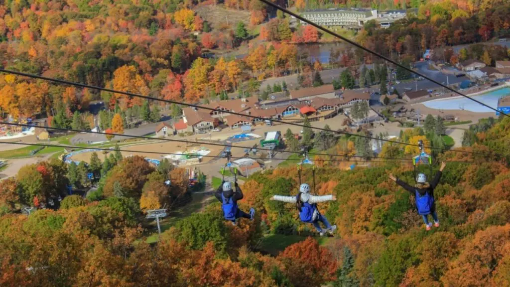 Three people ziplining during the fall at Camelback Resort